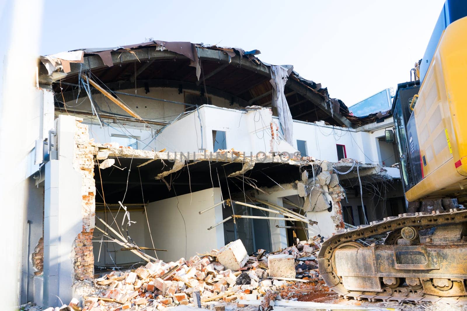 Demolition of a old building with sloopkraan against blue clouds sky.