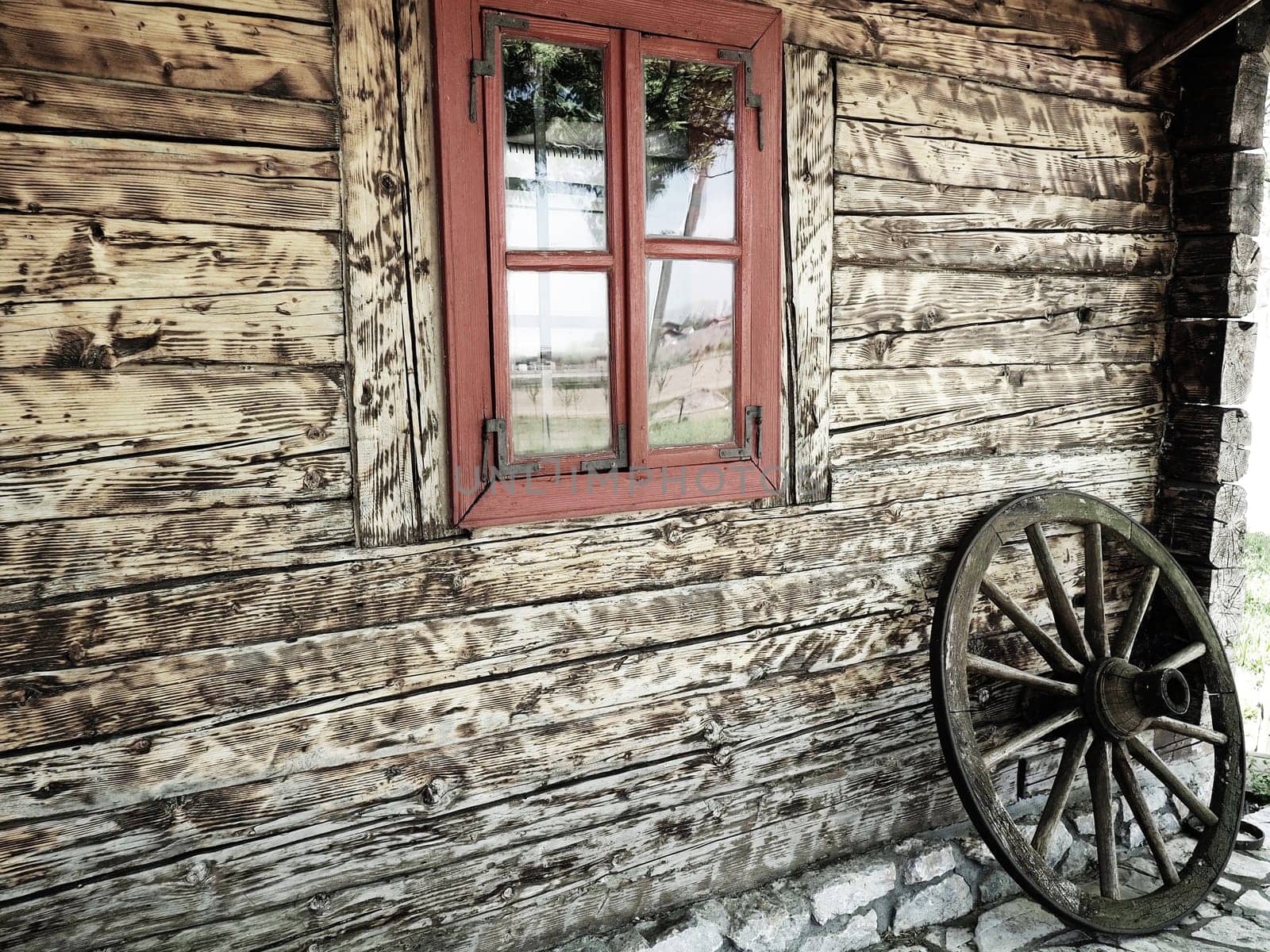 Stanisici, Bijelina, Bosnia and Herzegovina, 25 April 2021. Log village farmhouse. 19th century Bosnian mountain traditional dwelling. Restored ethno building. Antique wooden wheel from chariot.