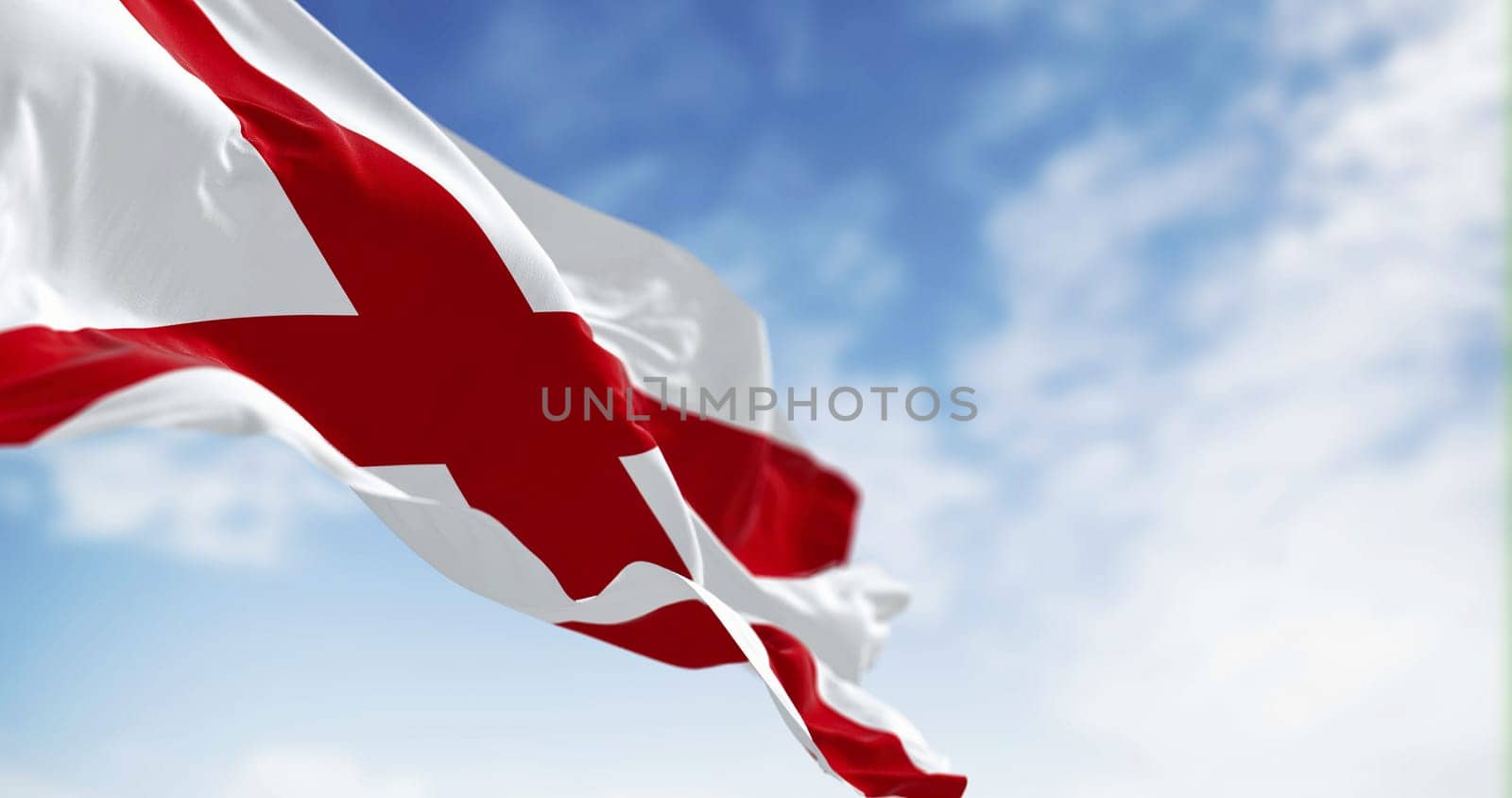 The state flag of Alabama waving in the wind on a clear day. Saint Andrew’s cross on a white background. 3D illustration render. Rippled textile
