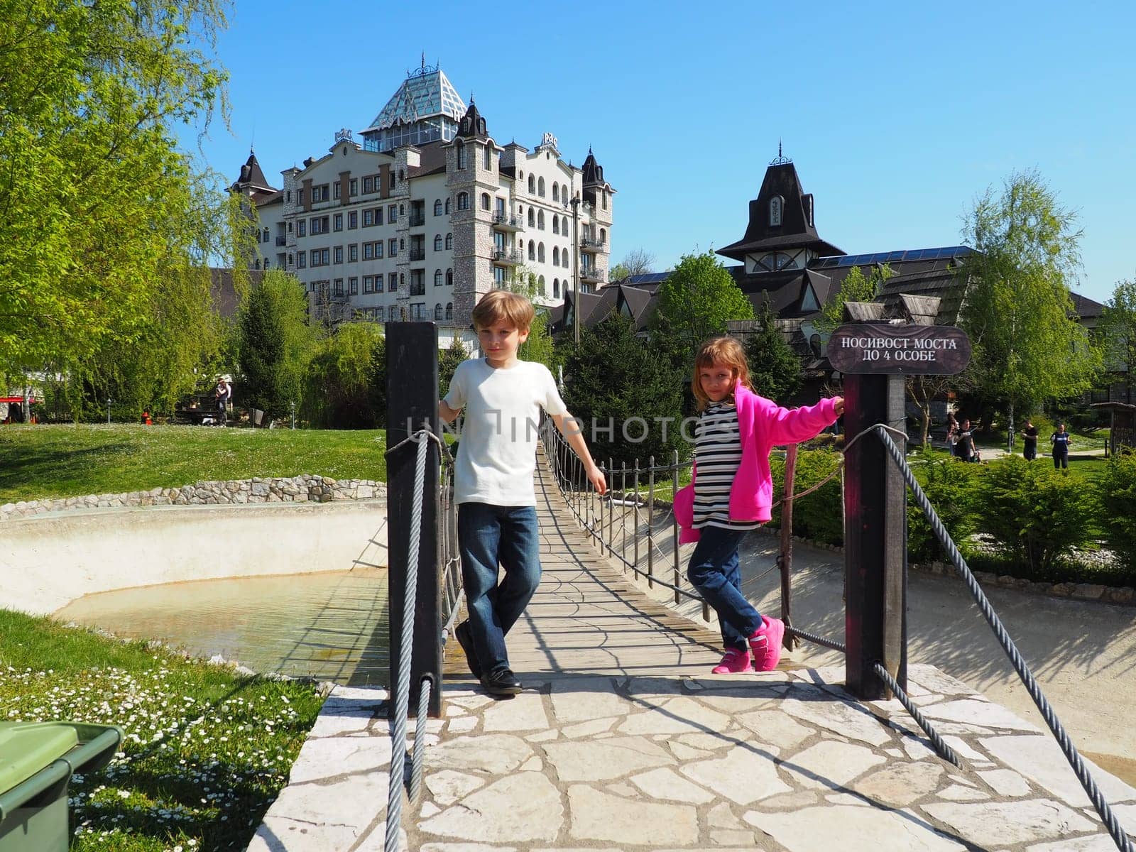 Stanisici, Bijelina, Bosnia and Herzegovina April 25 2021 A boy 8 years old and girl 7 years old, brother and sister, stand at the suspension bridge in the ethno village. Children visit tourist sites.