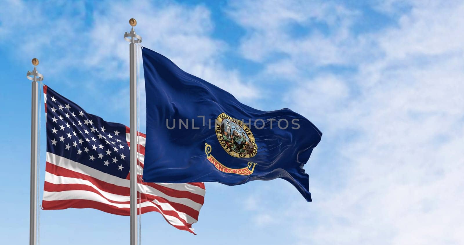 The Idaho state flag waving along with the national flag of the United States of America on a clear day. 3D illustration render. Rippled textile
