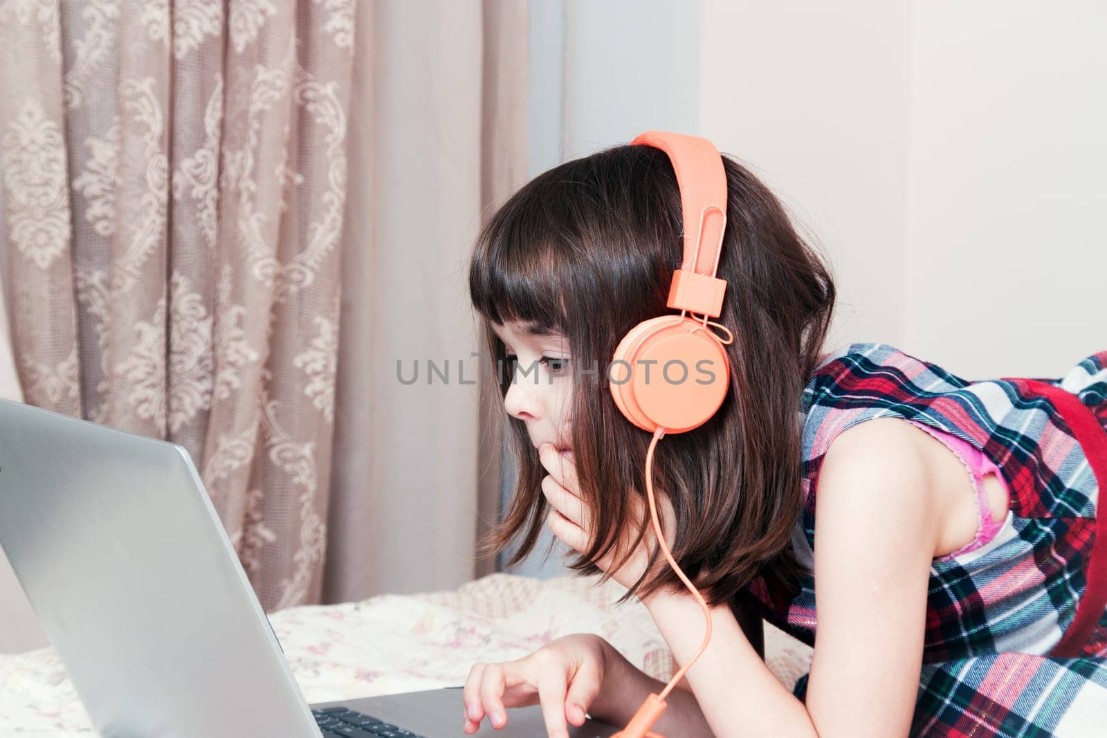 Little girl using the laptop with earphones