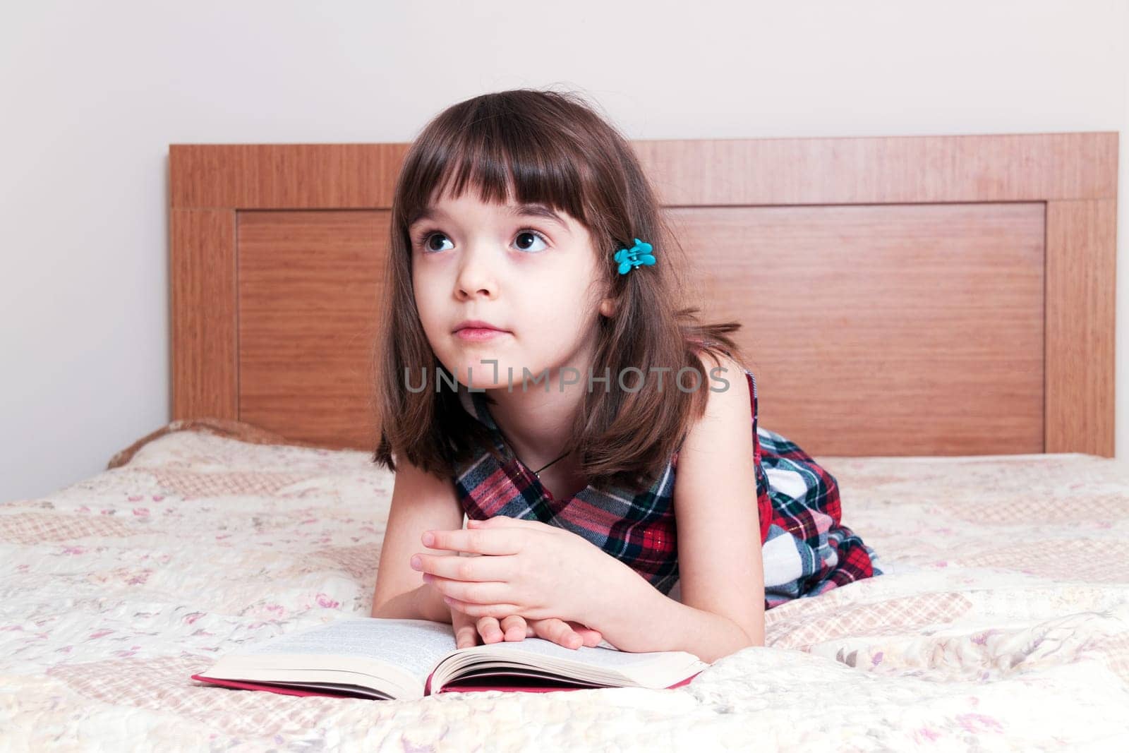 Little girl reading a book at home