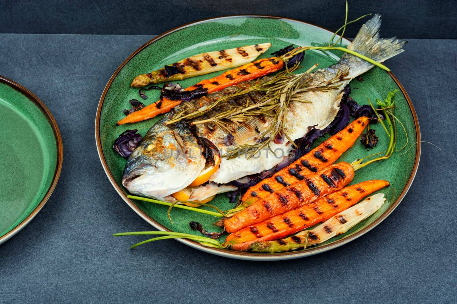 Baked dorado fish or sea bream with grilled vegetables on concrete background. Flat Lay