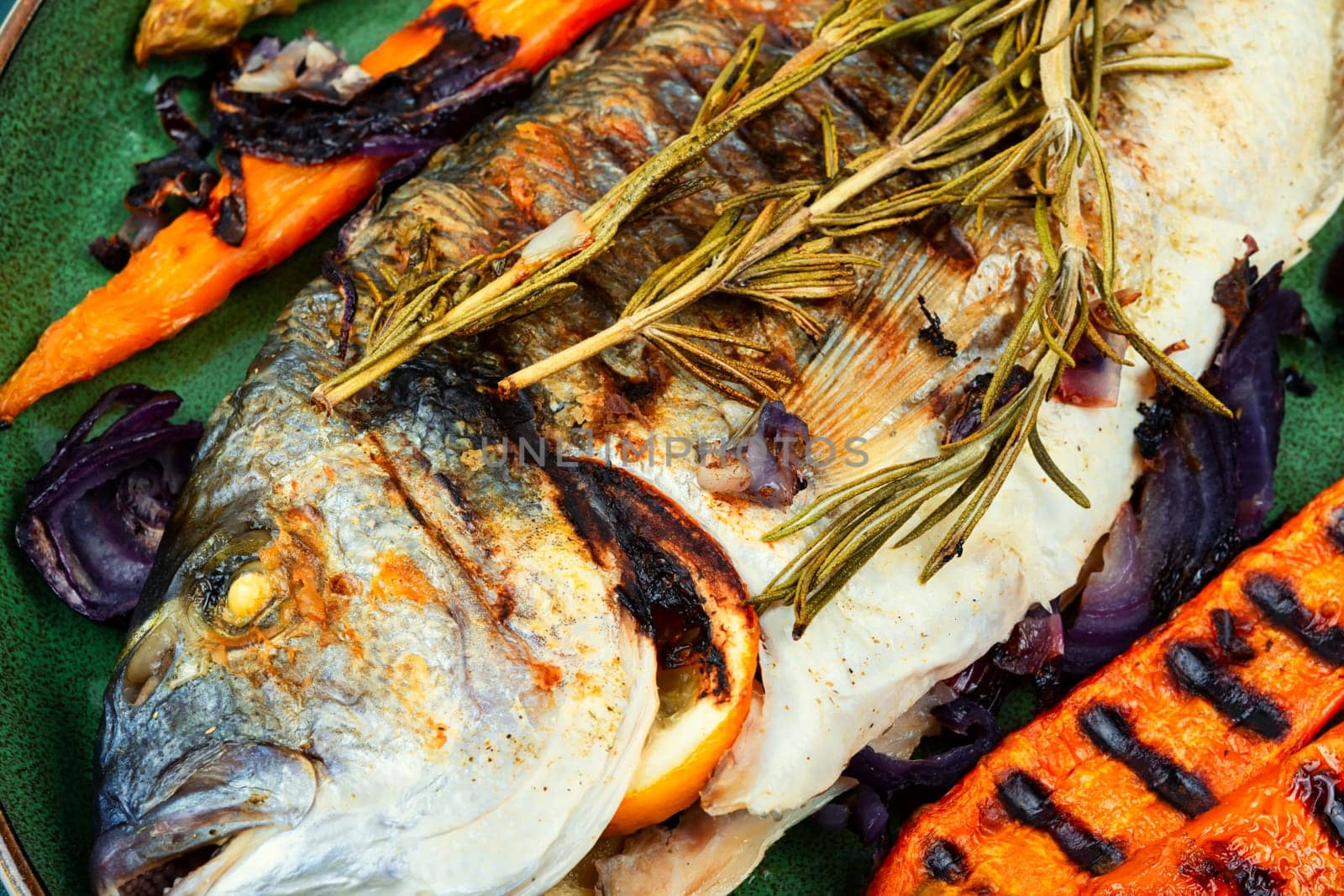 Baked dorado fish or sea bream with grilled vegetables on concrete background. Flat Lay