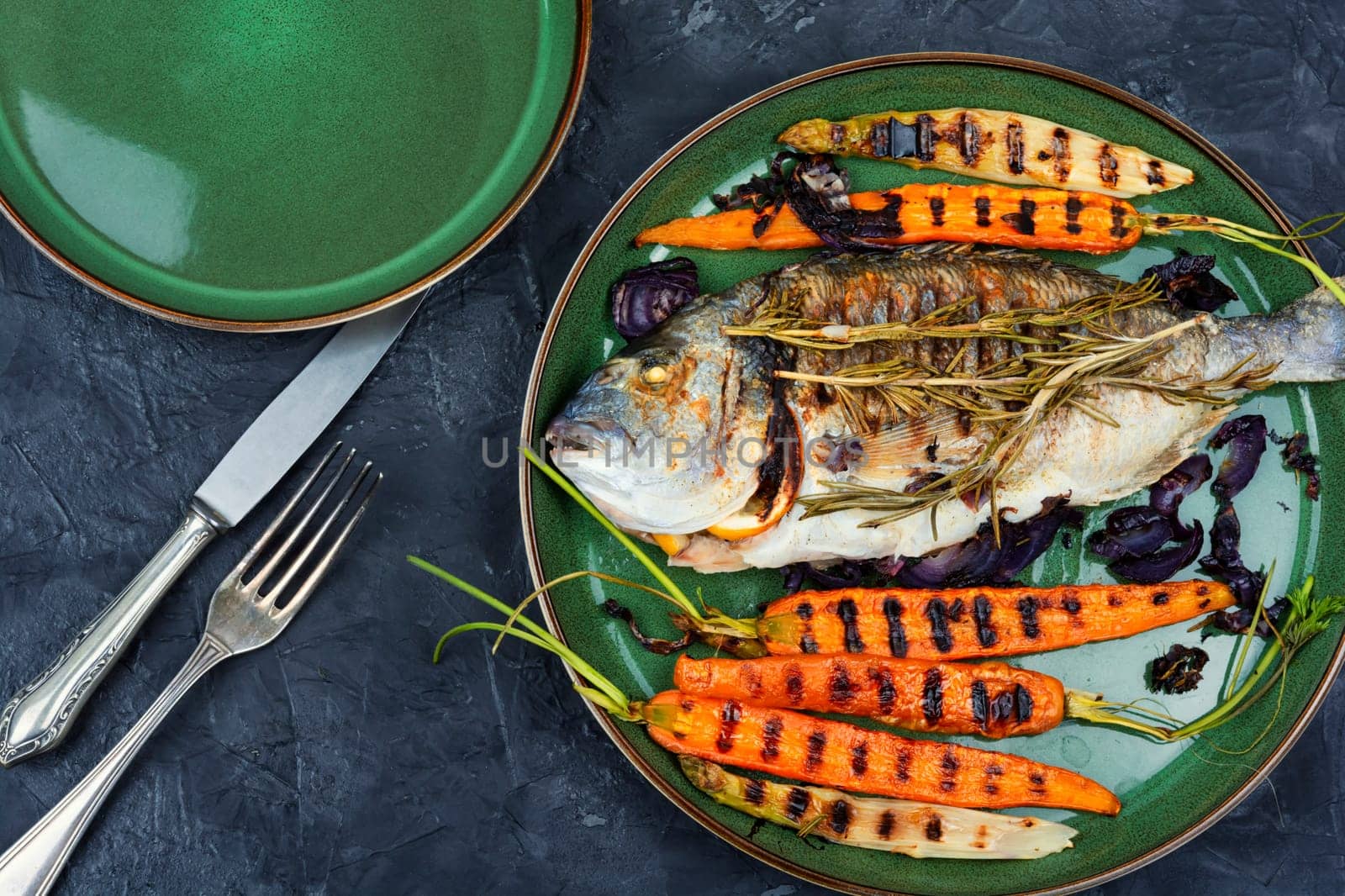 Baked dorado fish or sea bream with grilled vegetables on concrete background. Flat Lay