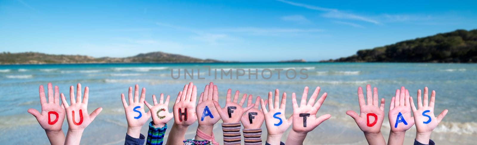 Children Hands Building Colorful German Word Du Schaffst Das Means You Can Do It. Summer Ocean, Sea And Beach As Background.