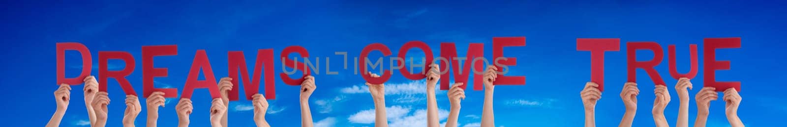 People Or Persons Hands Building English Word Dreams Come True. Summer Ocean, Sea And Beach As Background.