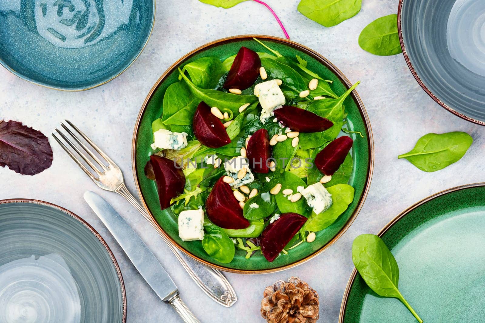 Beetroot salad with beets, blue cheese, herbs and pine nuts on the green plate