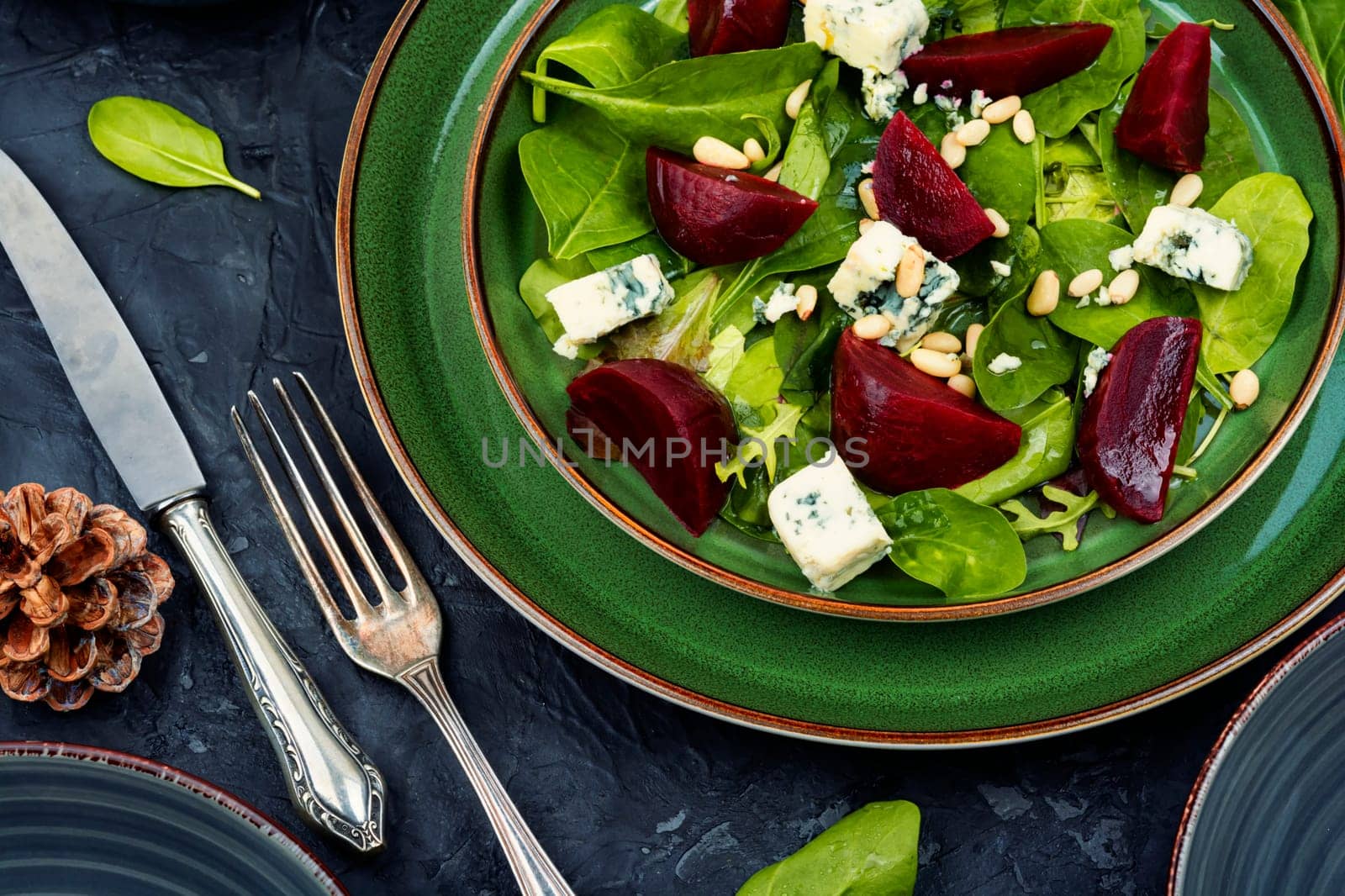 Beetroot salad with beets, blue cheese, herbs and pine nuts on the green plate