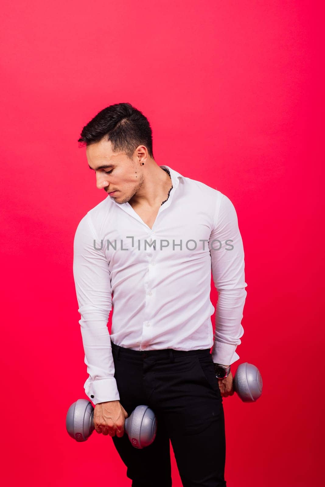 Business man with fitness dumbbells wear shirt. Studio shoot on red background