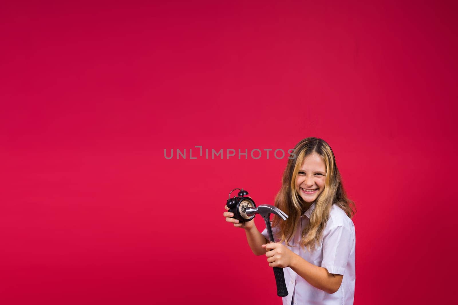 Kid girl holding hammer and alarm clock smiling with happy and cool smile on face. showing teeth.