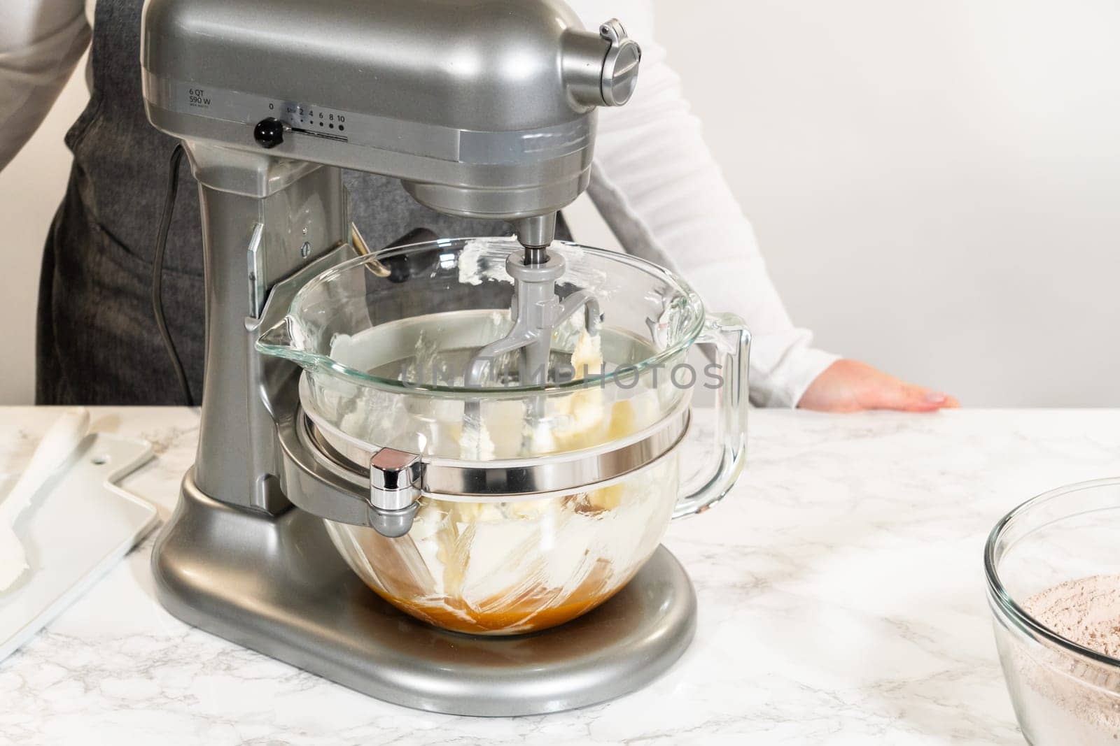 Stand mixer with butter, brown sugar, and other ingredients for Pale Gingerbread Cookies with Subtle Spice Flavor. Glass bowl on the mixer is partially filled.