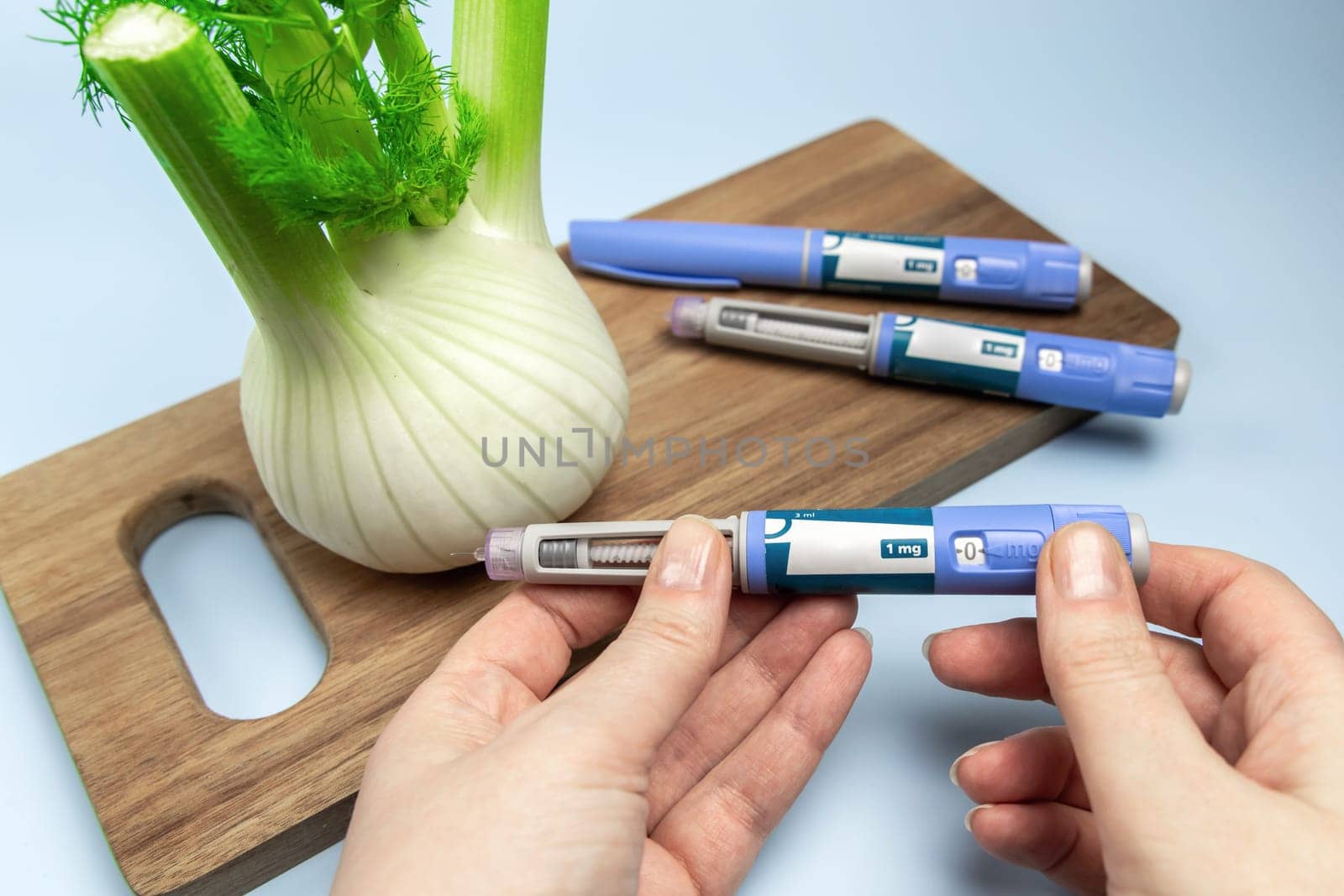Hands holding Insulin injection pen and fennel vegetable root for diabetics and weight loss. High quality photo