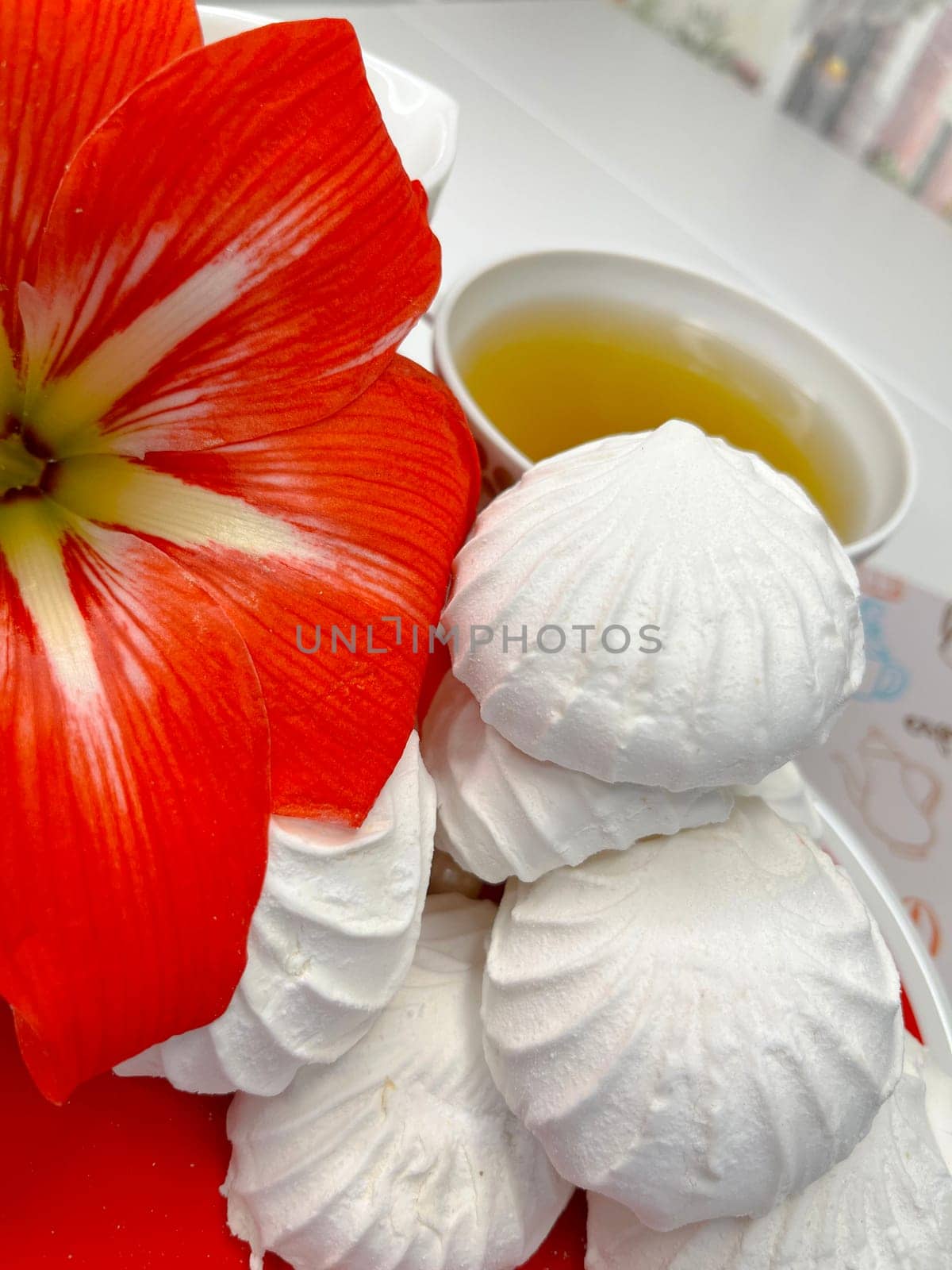 a few marshmallows on a saucer, a cup of fragrant tea and an amaryllis flower