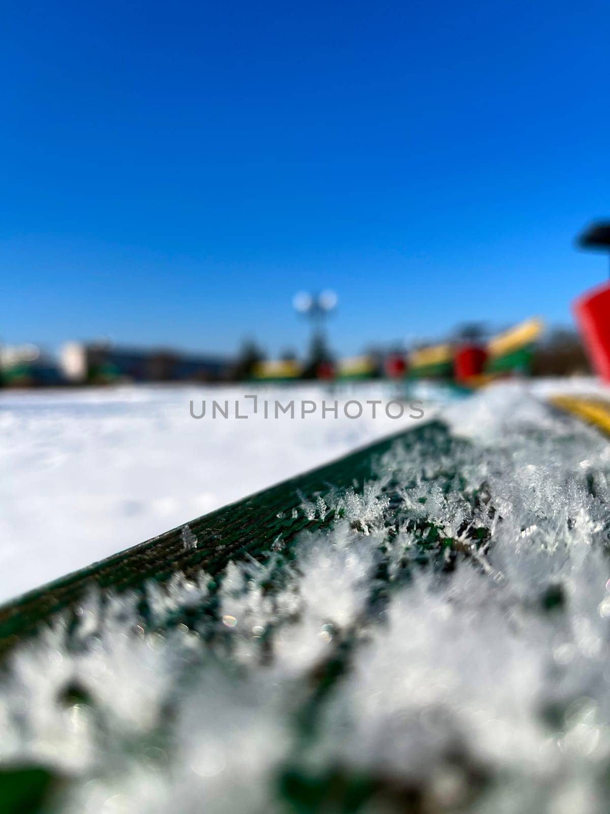 under the snow, colorful benches in winter on the city embankment