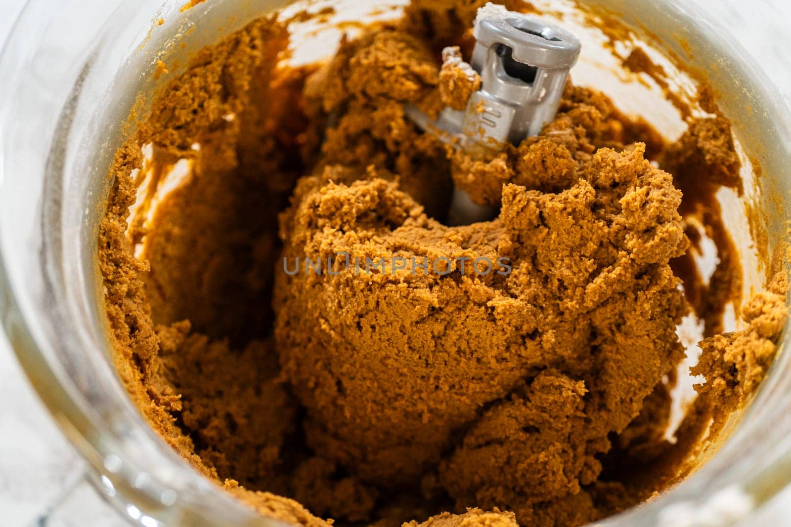 A close-up of the thick, dark Classic Gingerbread Cookie Dough in the mixing bowl, showing the dense and well-blended texture. The dough is now ready for the next steps of rolling and cutting into festive shapes.