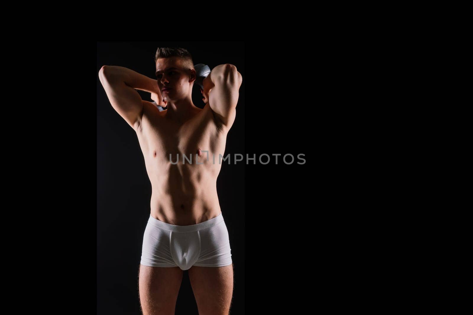 Shirtless bodybuilder holding a dumbell and showing his muscular arms.