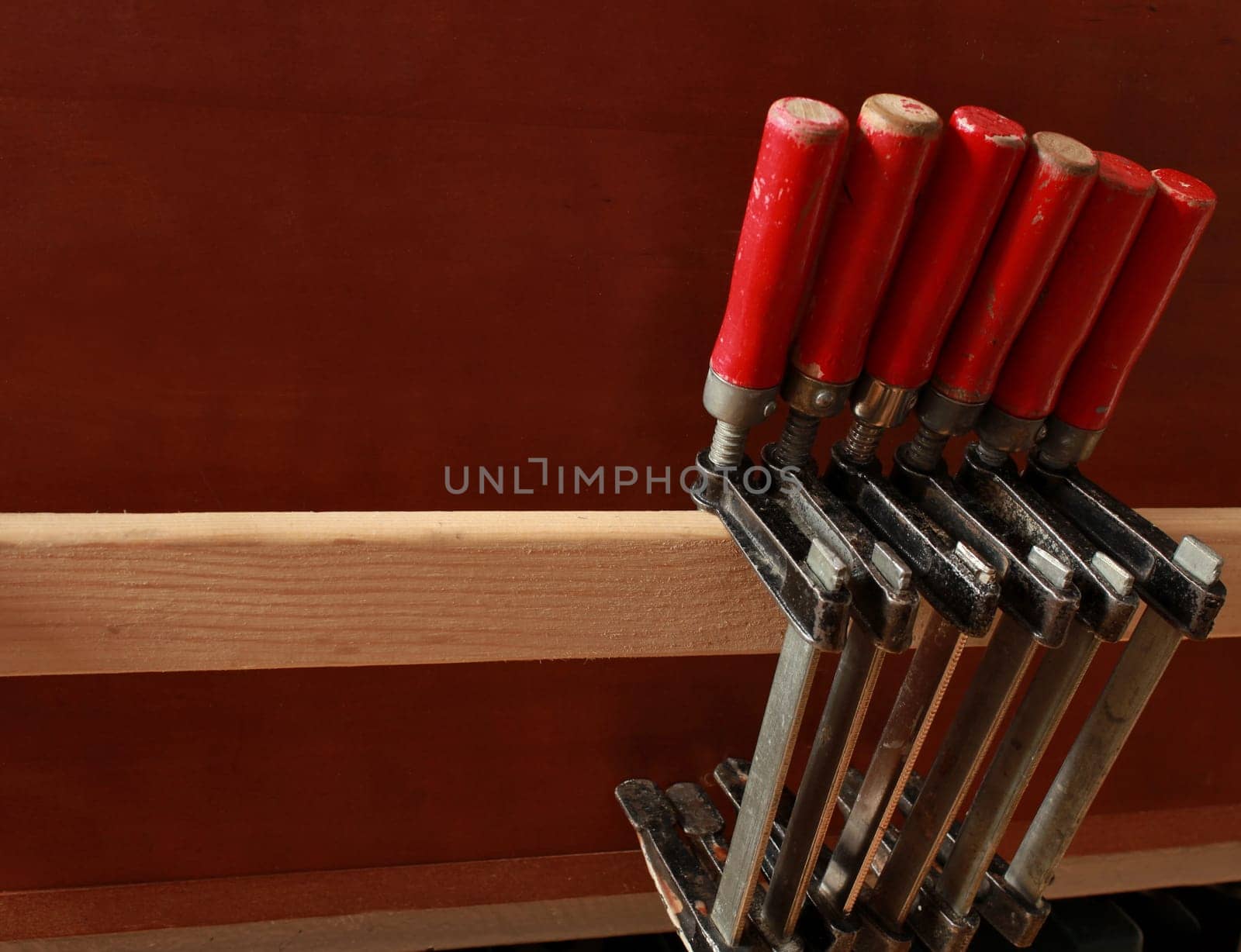 carpentry clamps with red handles hang on a shelf in a carpentry workshop