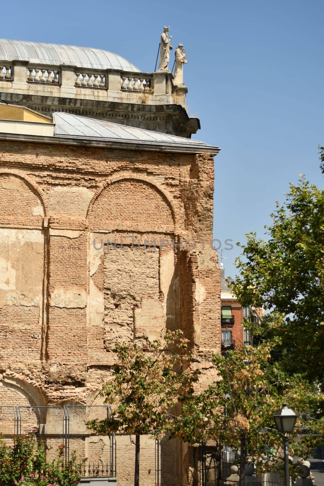 Vertical shot of a part of a historical building with two statues on a roof in Madrid, Spain