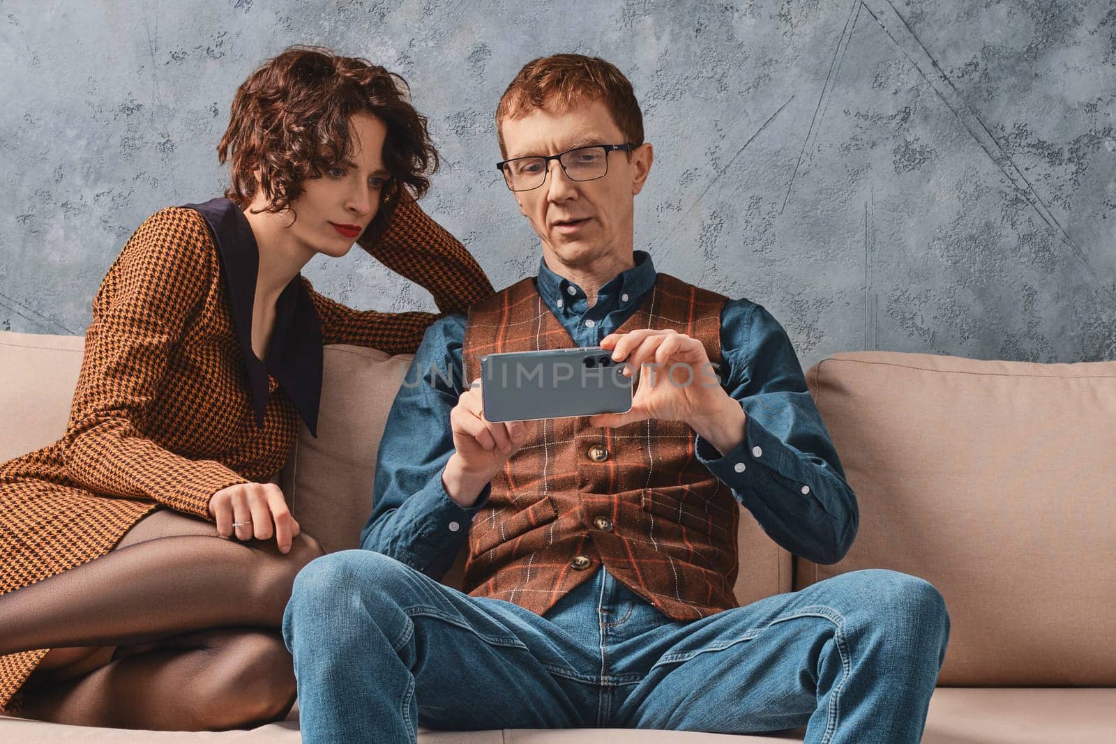 Middle aged man shows to his wife how to control their smart home from smartphone
