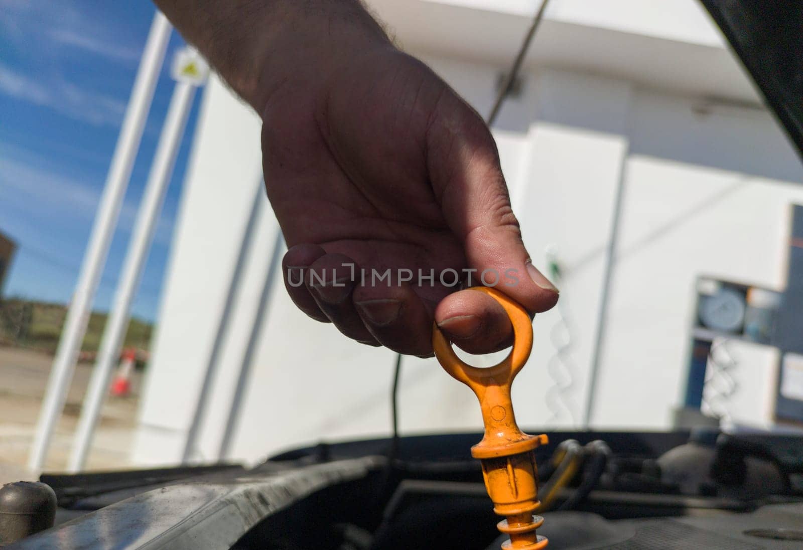 Man checking his oil level from old diesel engine. Petrol station background