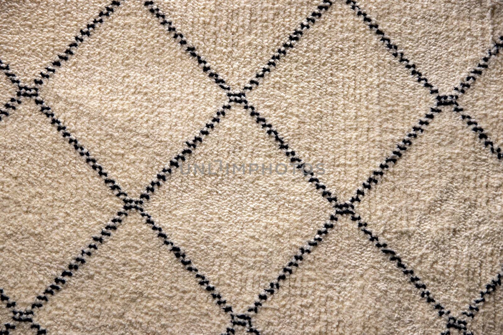 Beige fabric texture. Close-up of a light brown carpet textile background with a pattern of squares. Macro photograph. Beautiful bright backdrop with space.