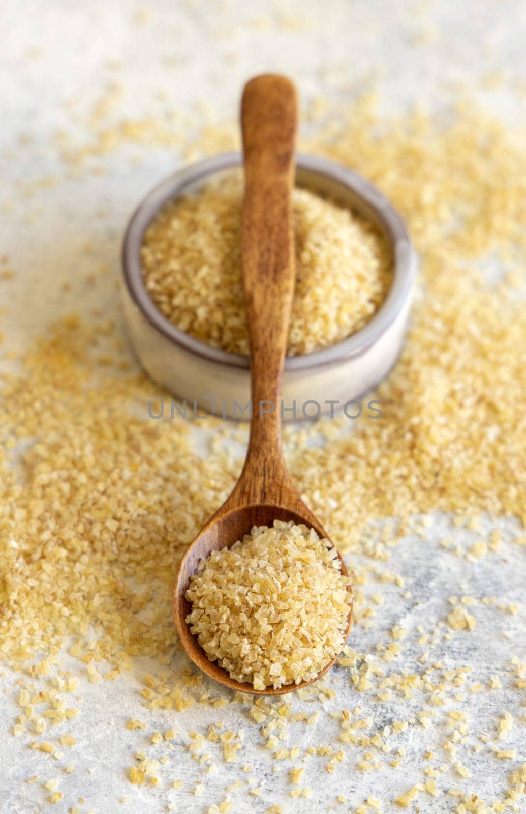 Wooden scoop and bowl with Dry uncooked bulgur wheat grain close up. Vegetarian and Vegan, Mediterranean and Middle Eastern cuisine. Healthy food
