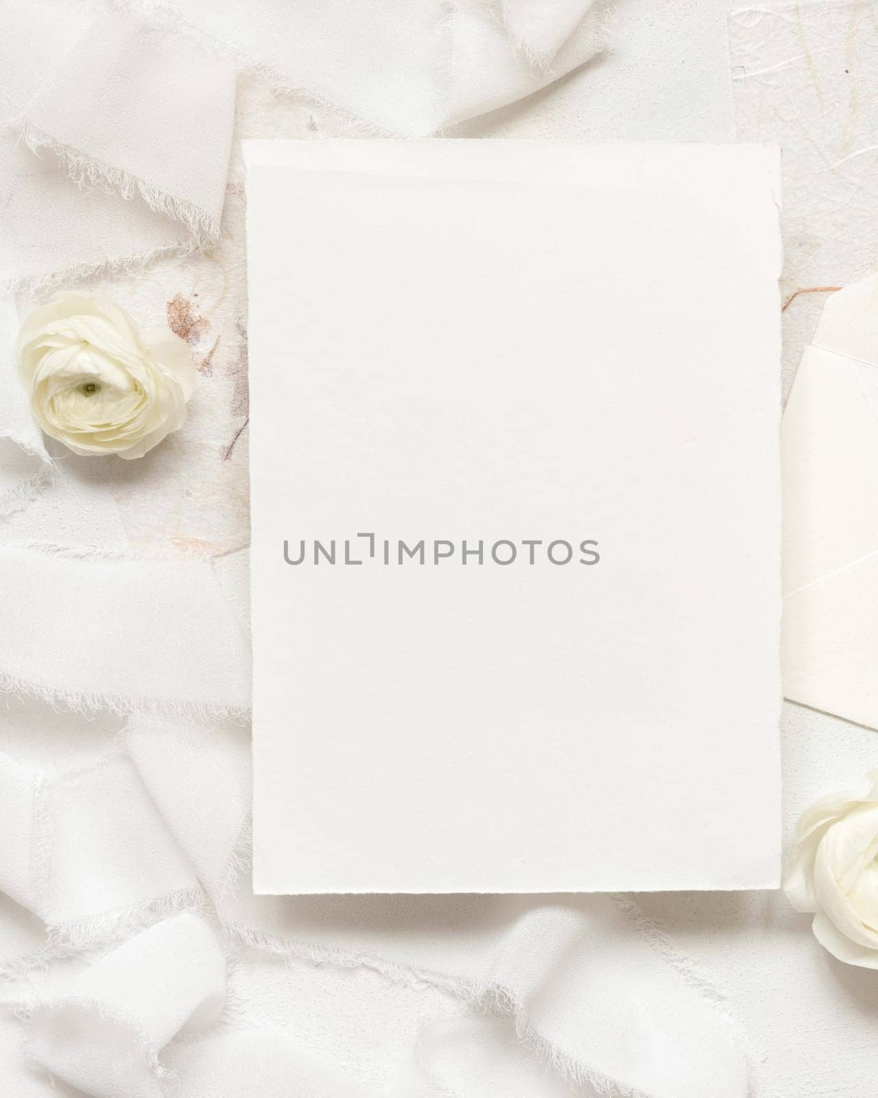 Blank card near cream roses and white silk ribbons top view, wedding mockup. Romantic scene with vertical card and pastel flowers flat lay. Valentines, Spring or Mothers day concept