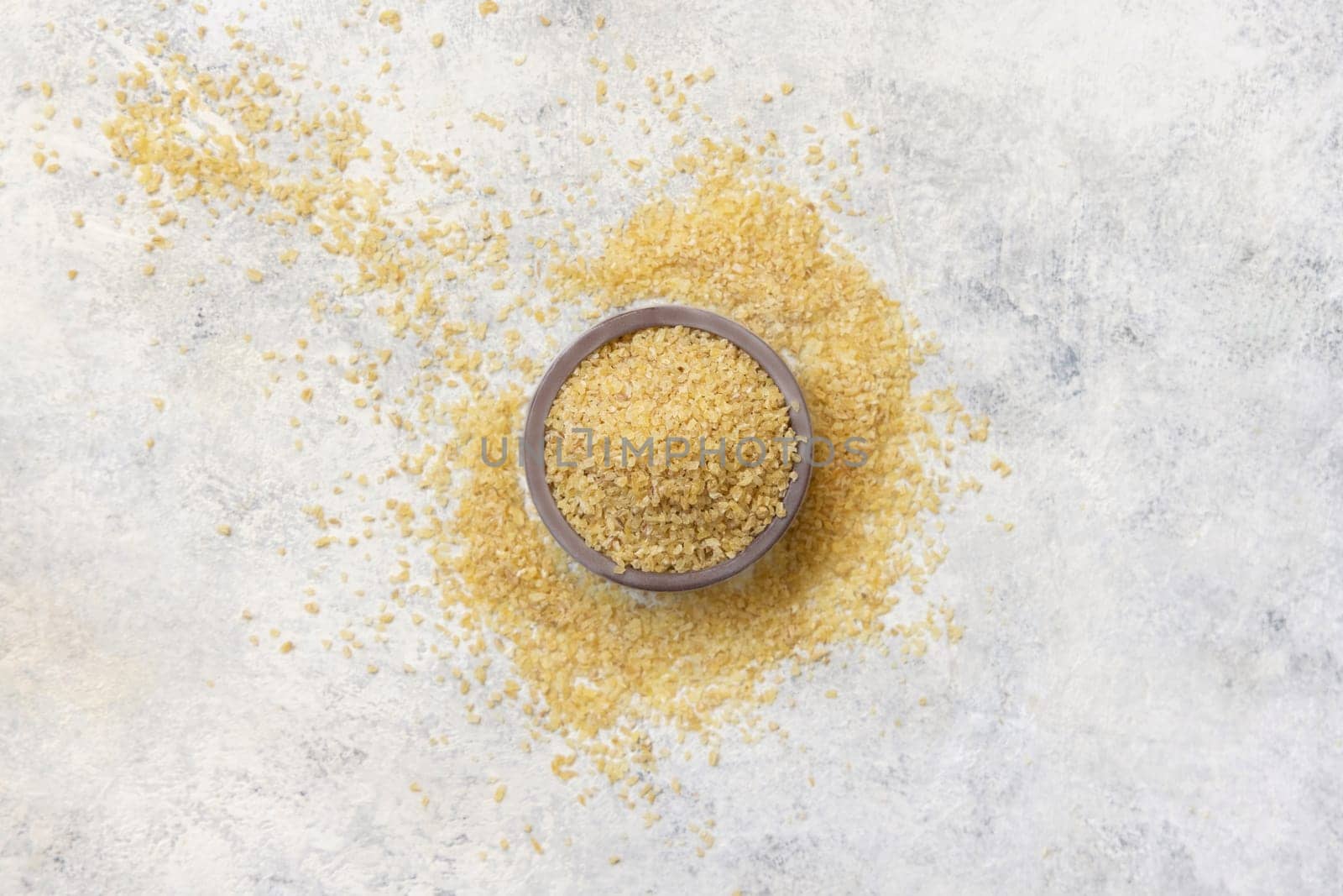 Wooden bowl with Dry uncooked bulgur wheat grain top view. Vegetarian and Vegan, Mediterranean and Middle Eastern cuisine. Healthy food