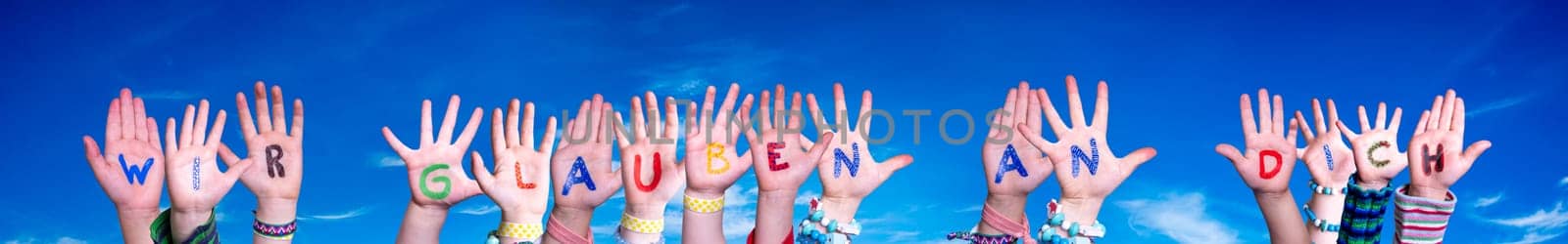 Children Hands Building Colorful German Word Wir Glauben An Euch Means We Believe In You. Blue Sky As Background.