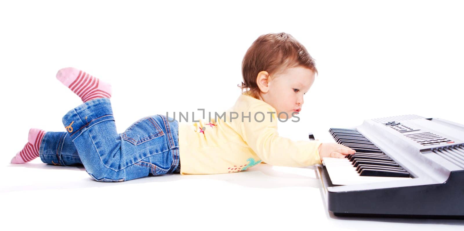 Baby lying on floor and playing synthesizer