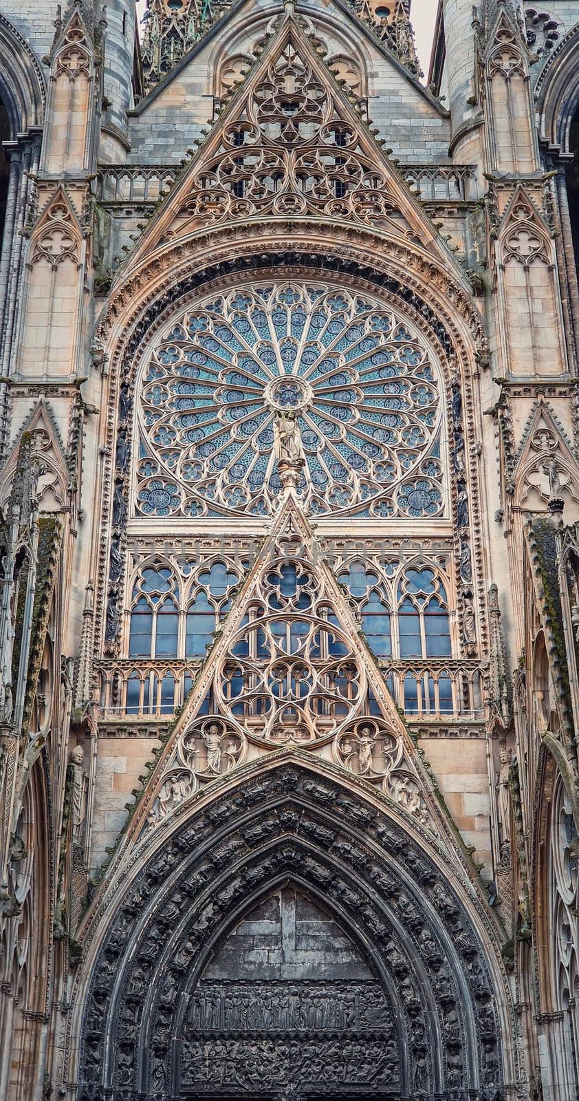 Architectural details of Notre Dame de Rouen Cathedral in the Normandy, France. Outdoor facade view of landmark featuring styles from Early Gothic to late Flamboyant and Renaissance architecture.