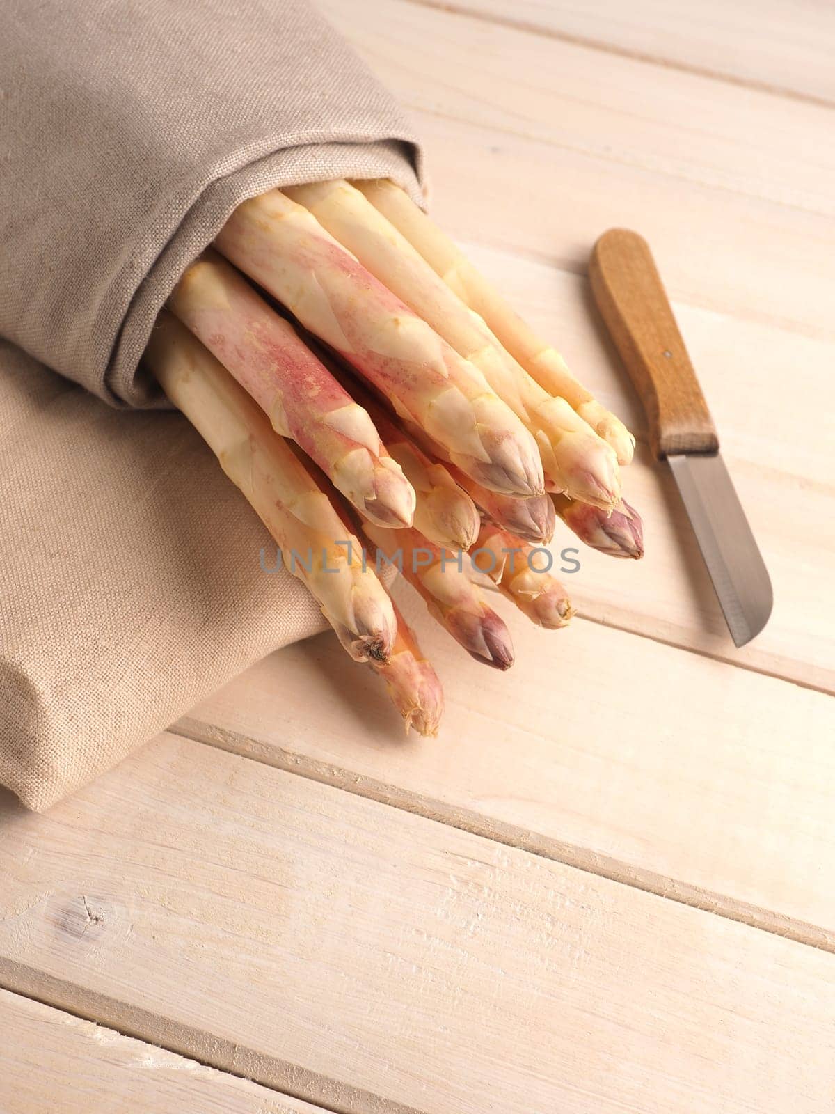 Tasty organic purple asparagus on a rustic wooden kitchen table, close up, healthy food
