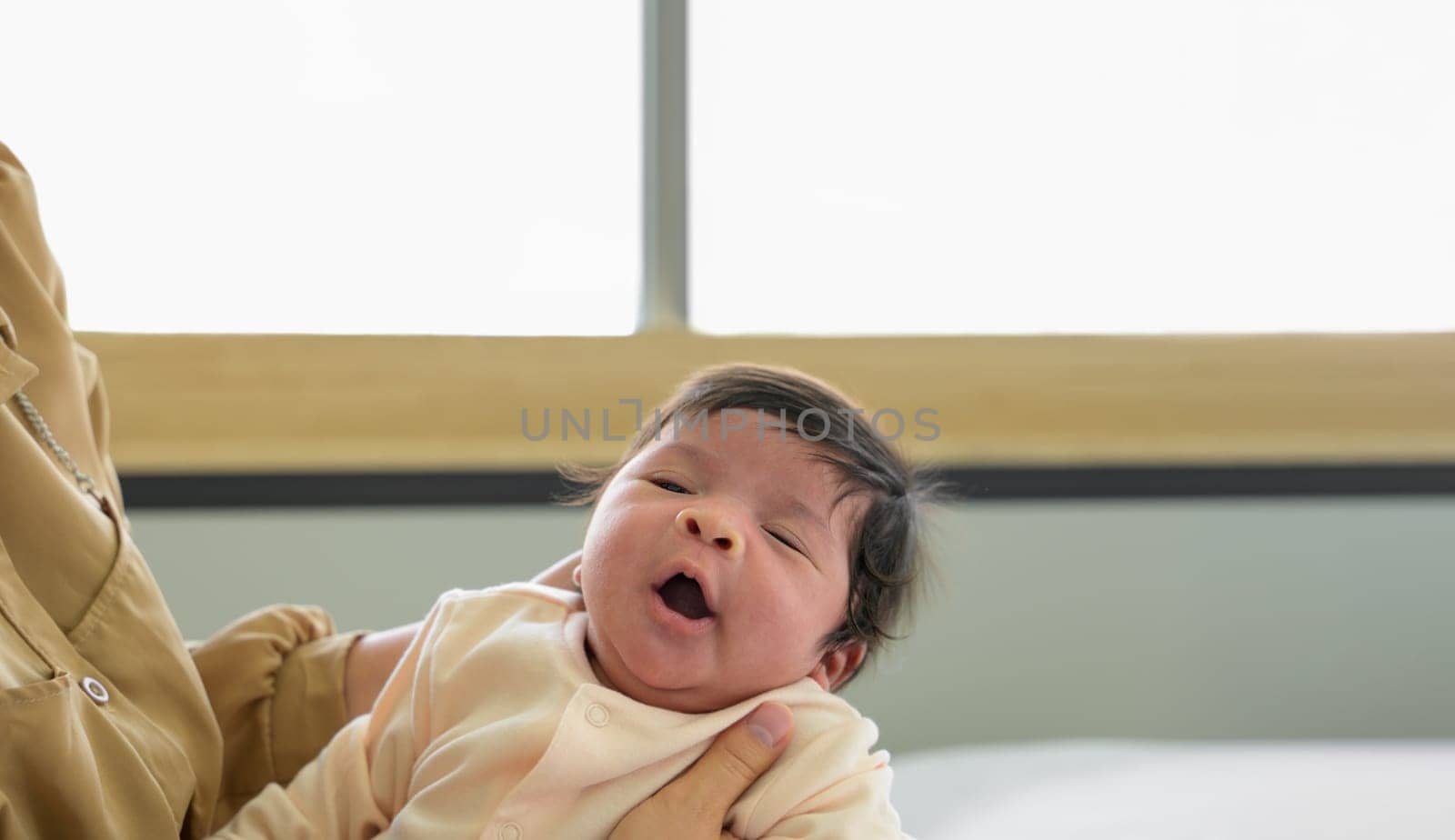 Adorable newborn baby girl yawn sleepy on mom hands. Healthy newborn baby concept
