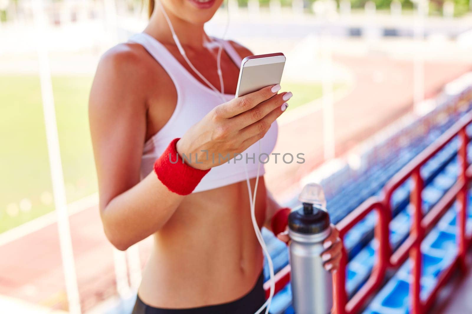 Modern girl with iphone writing sms at stadium
