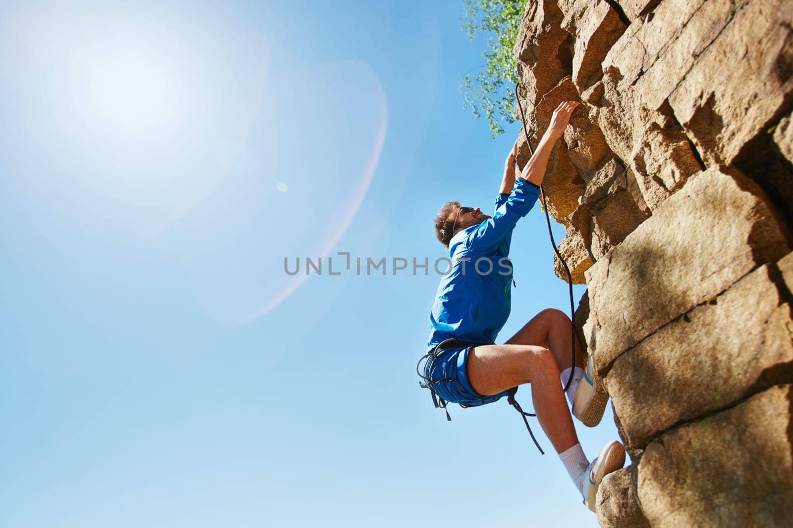 Young man climbing on top of rocky mount