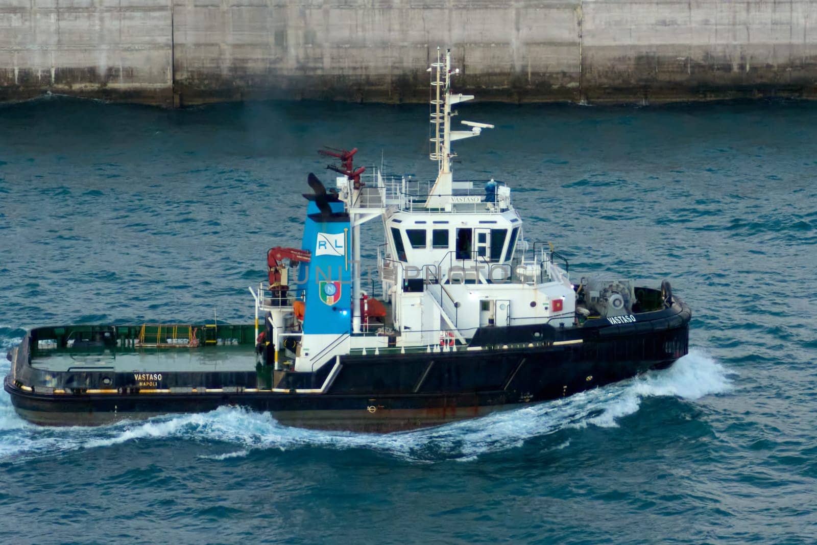 Civitavecchia, Italy, February 18, 2025: The Naples-based tugboat Vastaso is captured in action near a port, highlighting its role in port operations. To illustrate maritime and industrial activities.