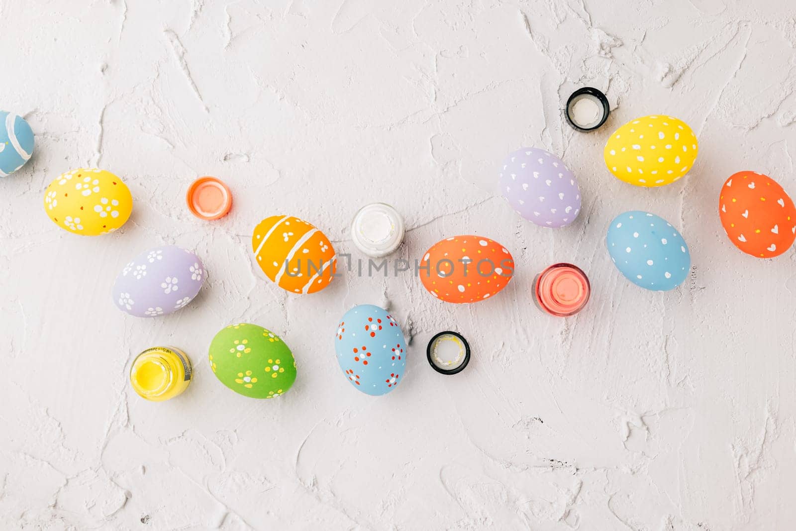 Easter Day Concept. colored multi-colored and paints brush painting easter eggs, colorful paints and paint brushes isolated on white cement background with copy space for text