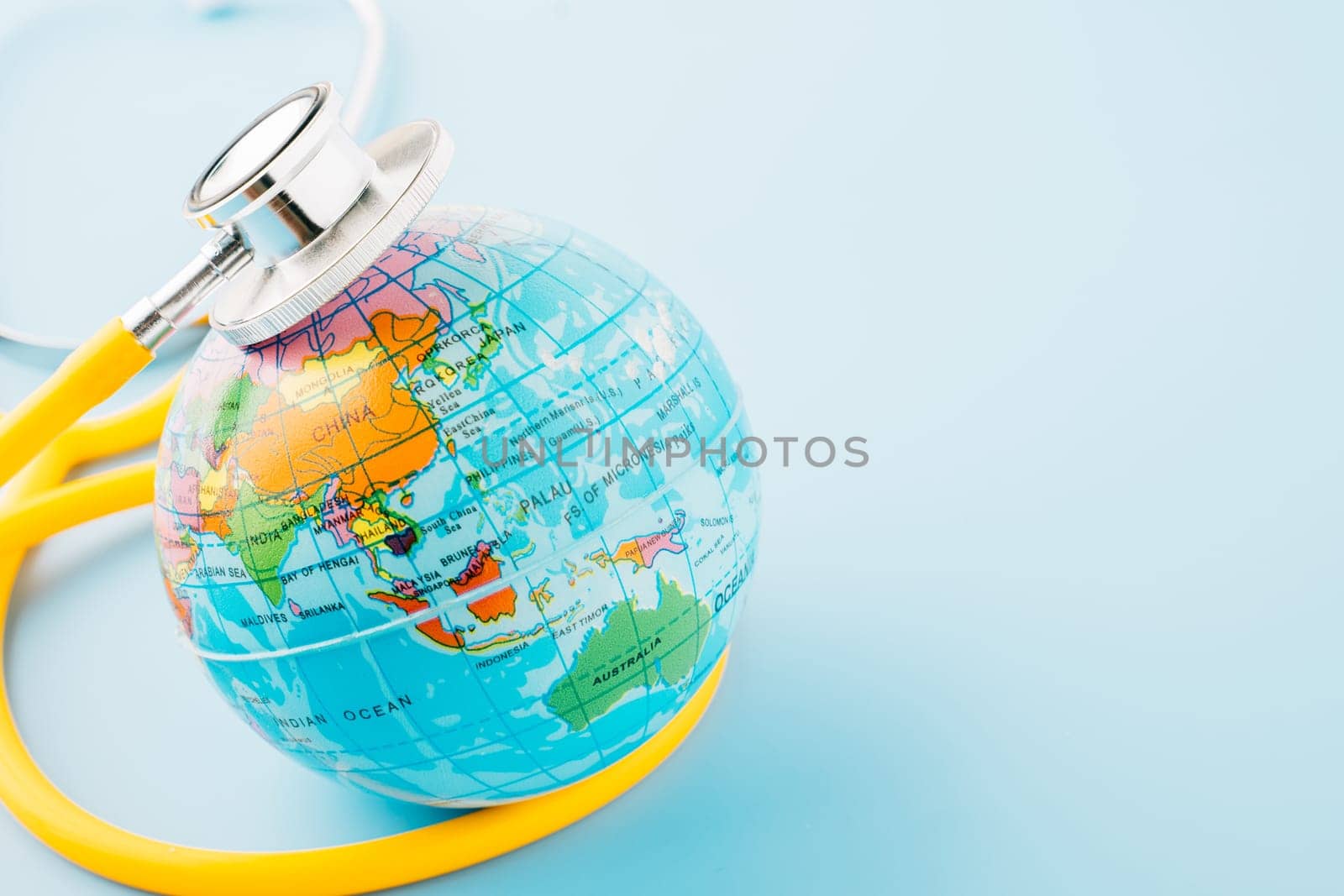 World Health Day. Yellow doctor stethoscope and world globe isolated on blue background, Save world day, Green Earth, Healthcare and medical concept
