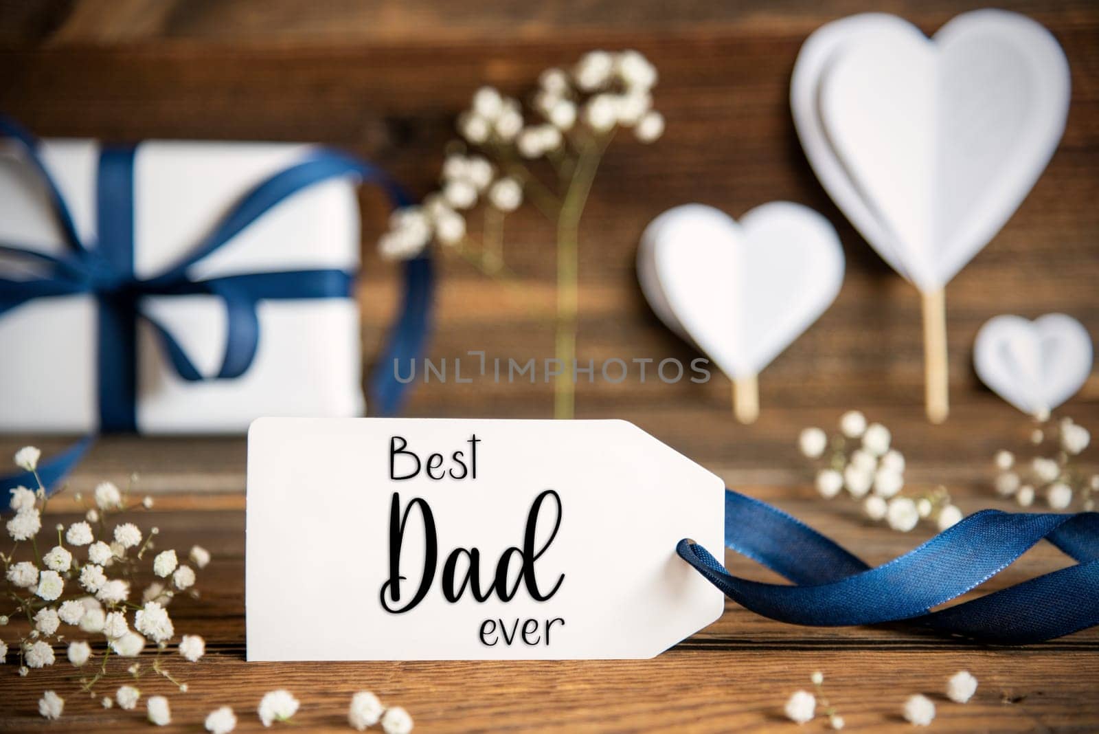 Label With English Text Welcome. White Festive Decoration Like Present With Blue Bow, Heart and Flowers. Vintage Wooden Background.
