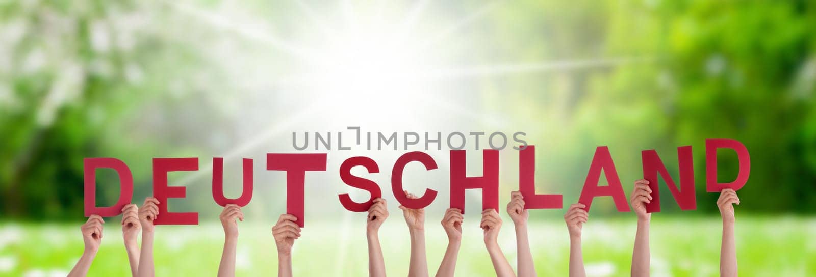 People Or Persons Hands Building German Word Deutschland Means Germany. Sunny Green Grass Meadow As Background.