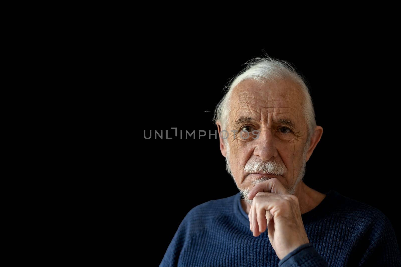 Beautiful gray hair old man wirh wrinkled face is posing on black background looking at the camera.