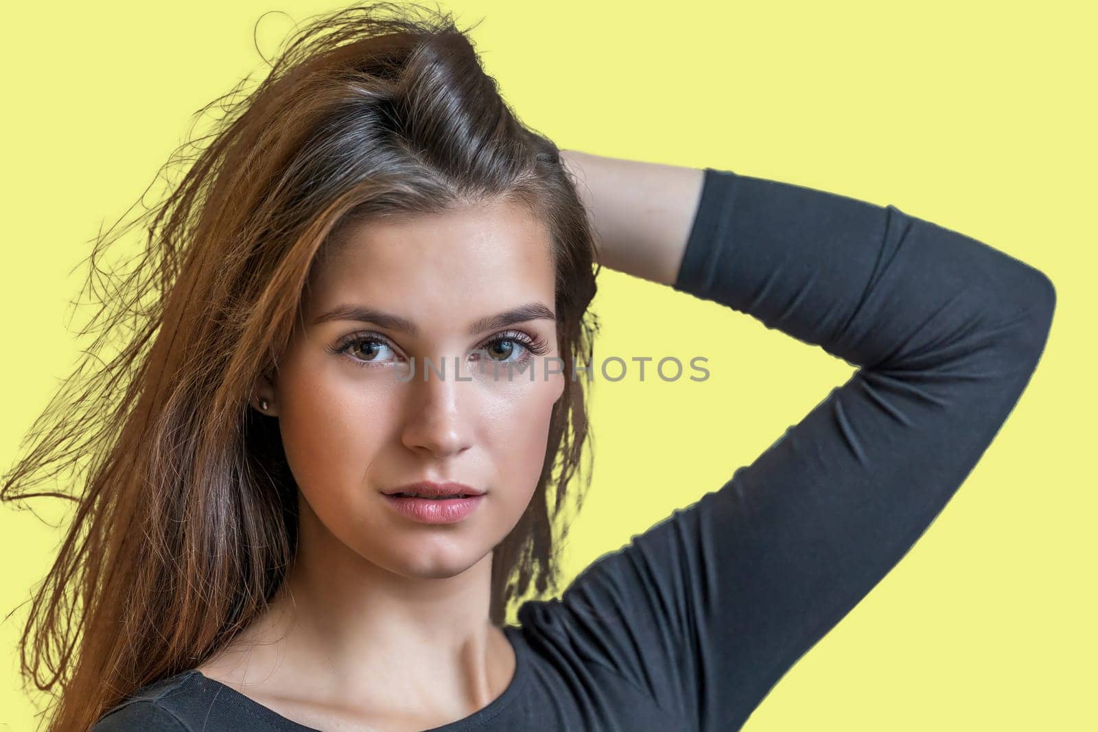 Portrait of beautiful long haired girl posing on yellow  background.  Horizontally.