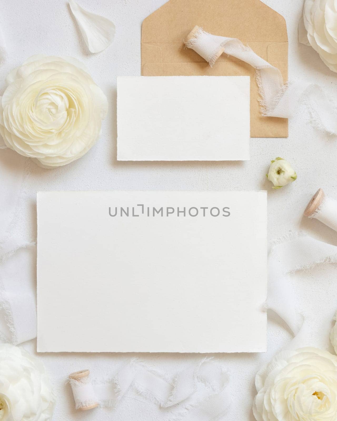 Blank cards near cream roses and white silk ribbons top view, wedding mockup. Romantic scene with horizontal cards and pastel flowers flat lay. Valentines, Spring or Mothers day concept