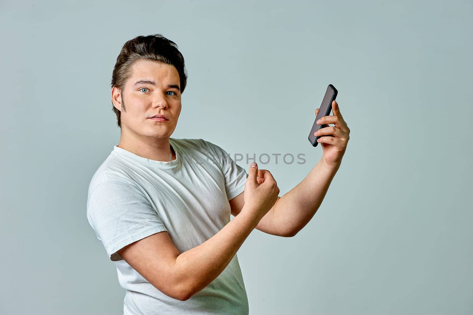 A man looks at the phone screen on a gray background. High quality photo