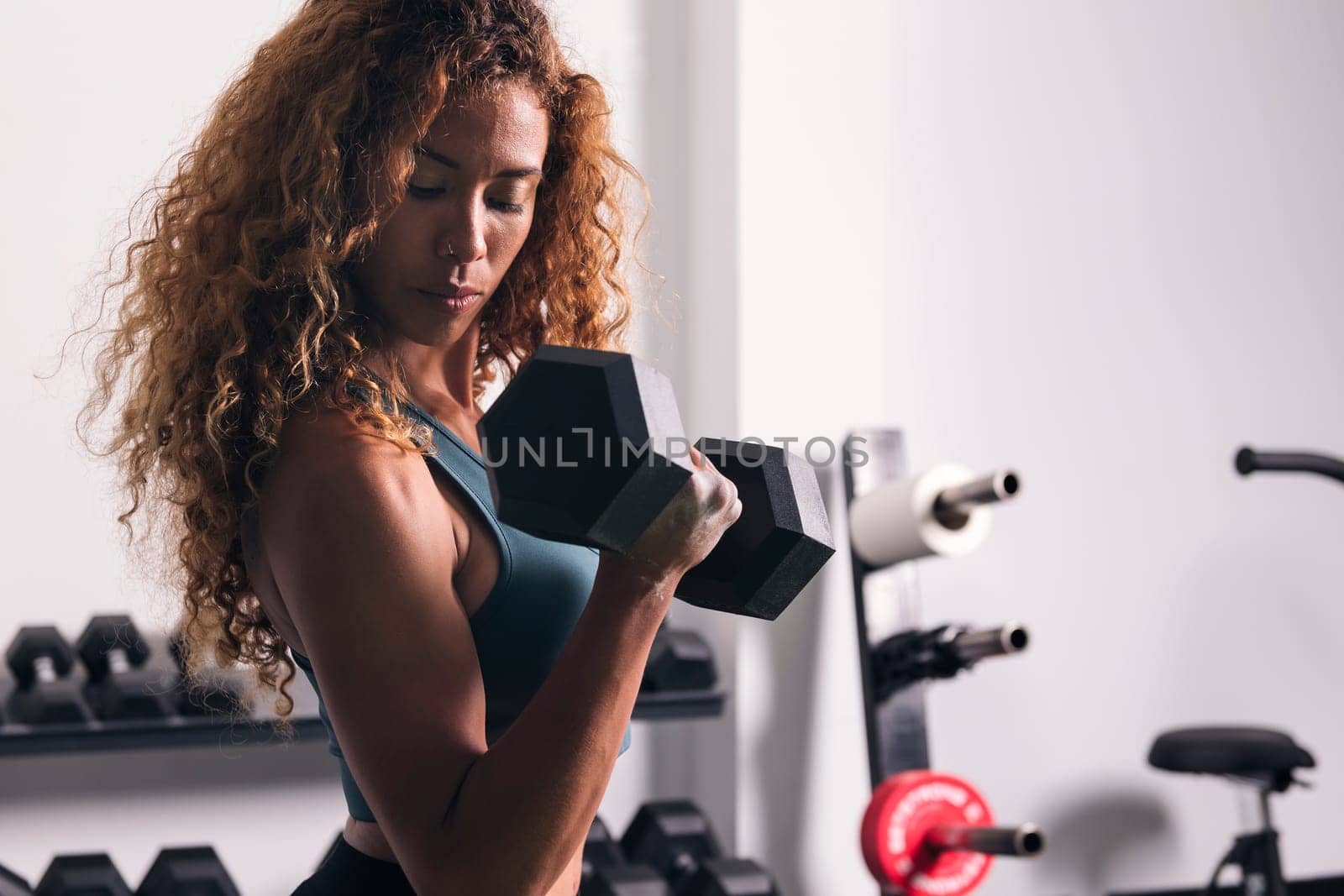 strong sportswoman doing exercise on biceps with dumbbells during workout at gym, concept of fitness and active lifestyle, copyspace for text