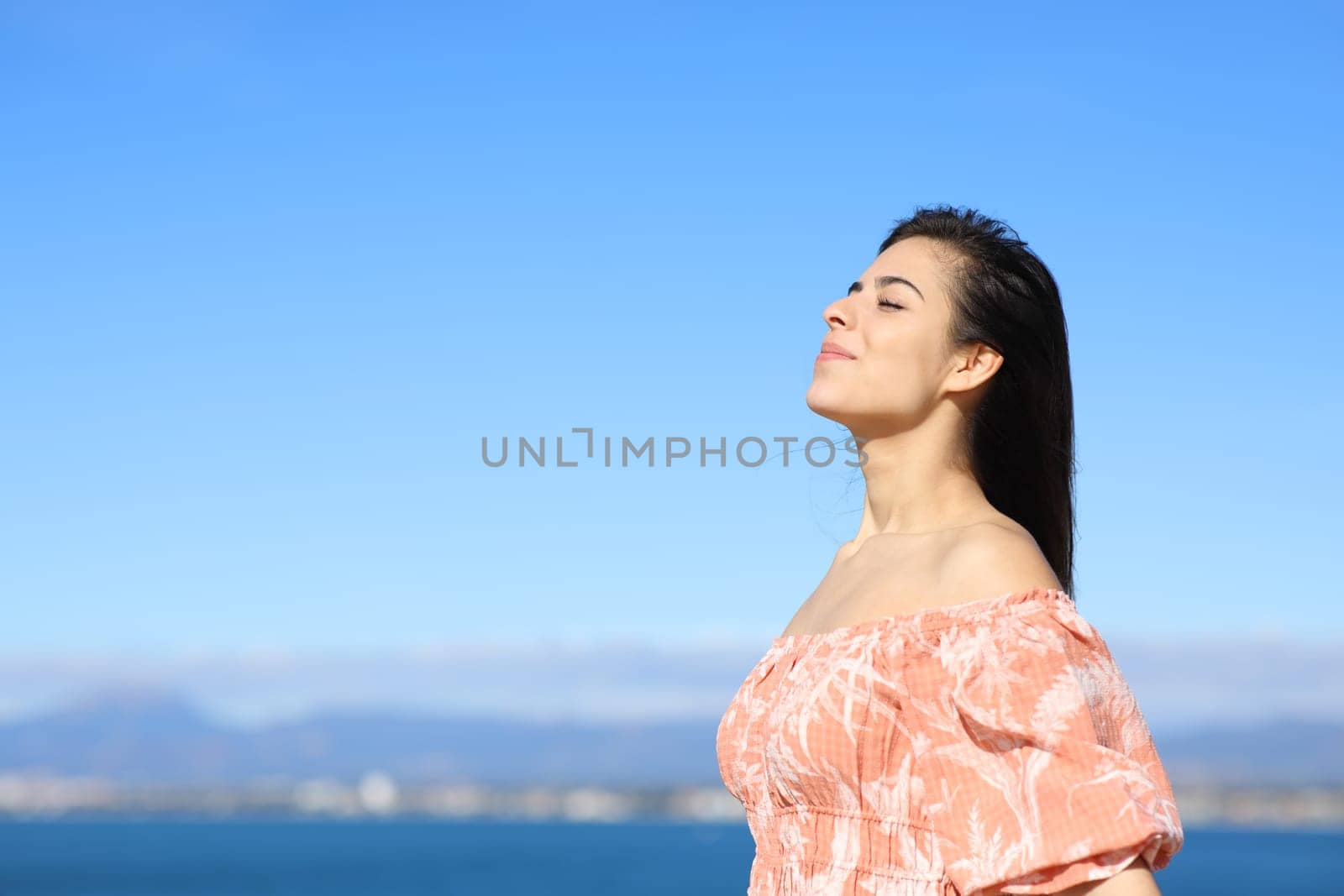 Happy woman breathing fresh air standing in the coast