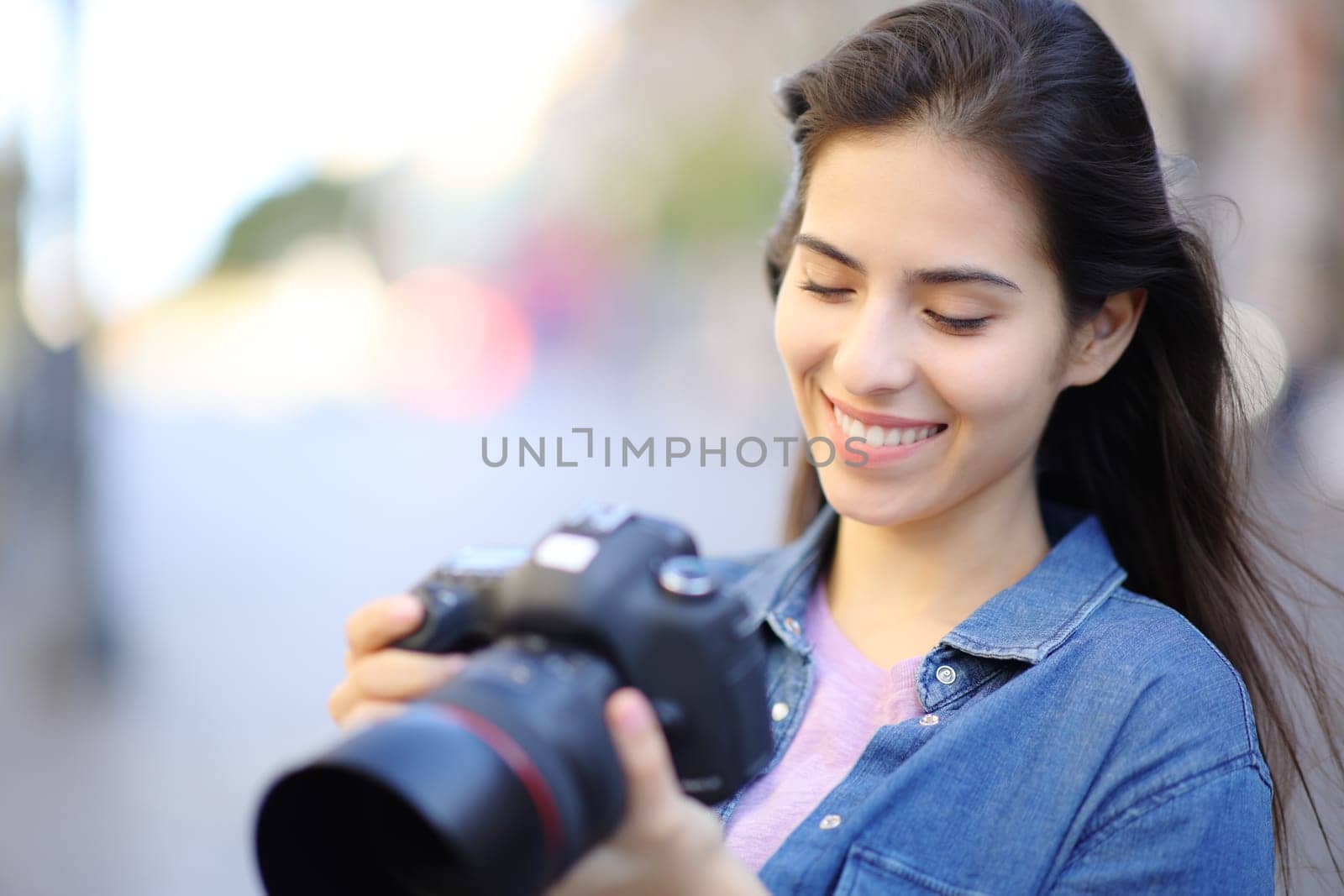 Happy photographer checking photos on camera outdoor in the street