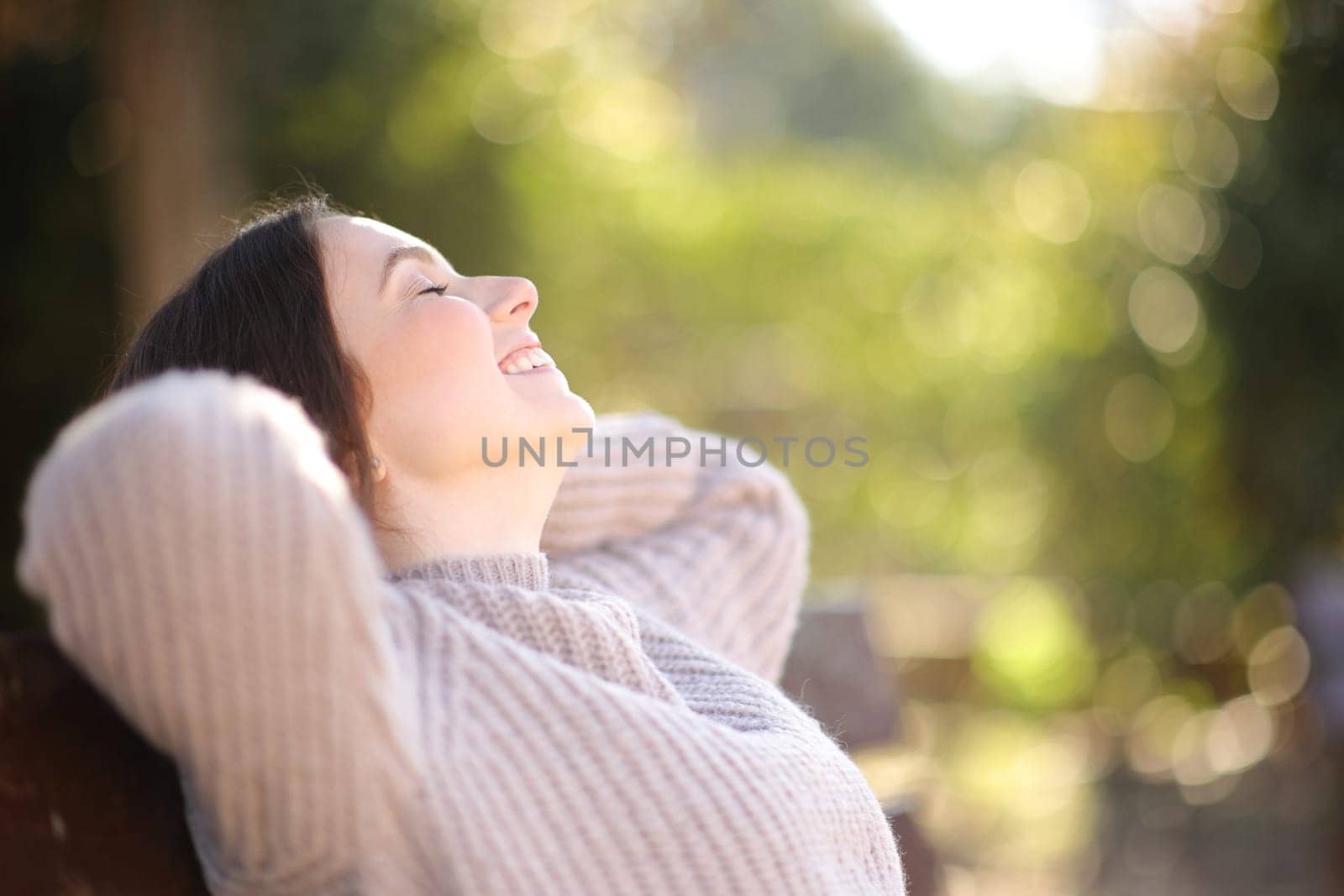 Profile of a relaxed woman resting sitting on bench in a park